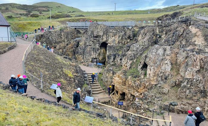 Several small groups of people heading to underground mine entrances, some exiting the underground mine and some standing on the pathways and a bridge